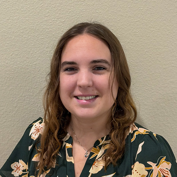 Dee Morse, Wellness Director at The Crestone Senior Living, smiling in a professional headshot, wearing a dark floral blouse and necklace, posed against a neutral indoor wall background.