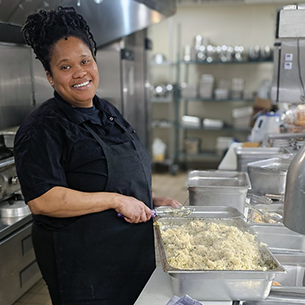 Culinary team member smiles while preparing a meal with fresh ingredients at The Crestone Senior Living.