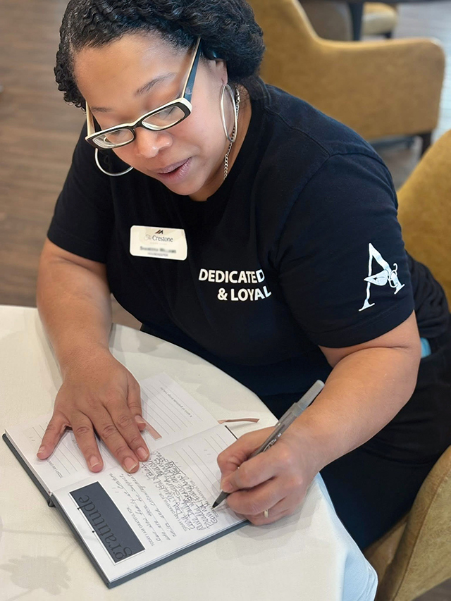 A woman on The Crestone Senior Living team writes thoughtfully in a journal.