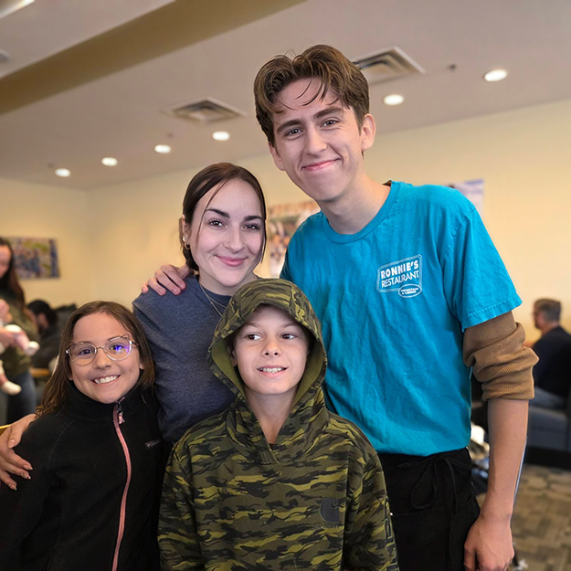 A woman and children smile alongside a local business owner.