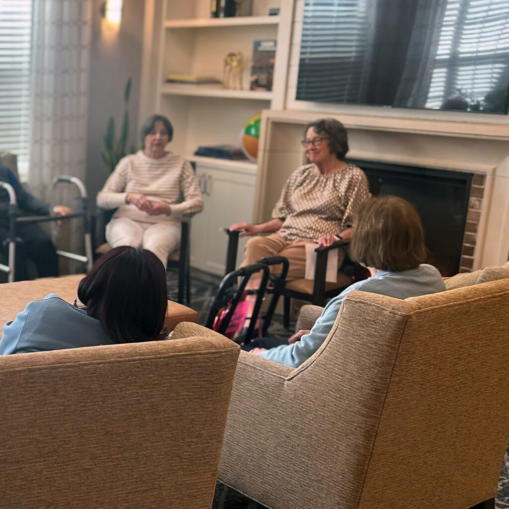 Residents at The Crestone gather in a warm, inviting room in cozy chairs.